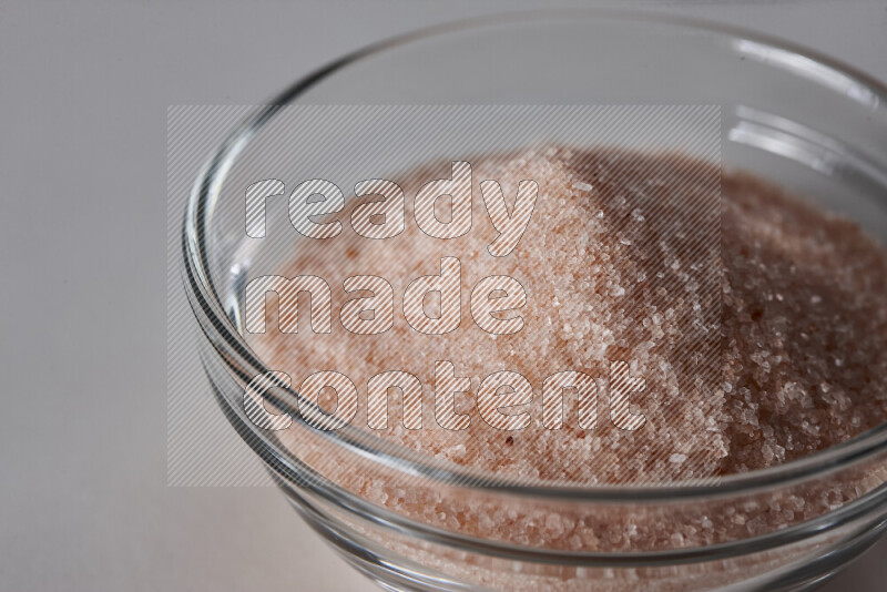 A glass bowl full of fine himalayan salt on white background