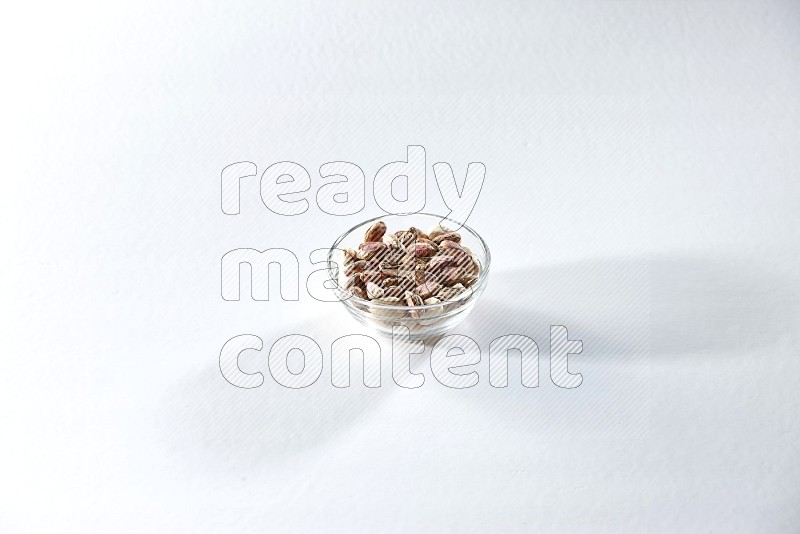 A glass bowl full of peeled pistachios on a white background in different angles
