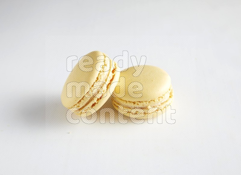 45º Shot of two Yellow Vanilla macarons on white background