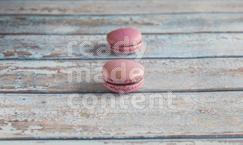 45º Shot of two Purple Strawberry macarons on light blue wooden background
