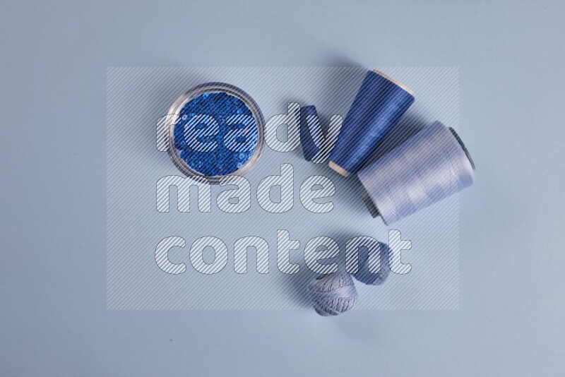 A blue collection of sewing and tailoring tools arranged on a blue background