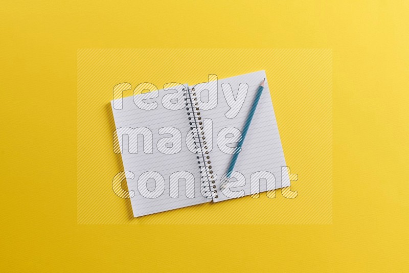 A blank open notebook with school supplies on yellow background (Back to school)