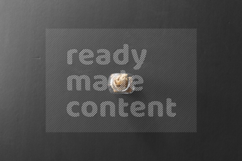 A glass spice jar full of ginger on black flooring