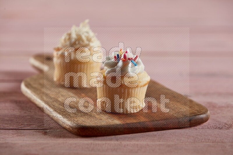 Vanilla mini cupcake topped with cream on a wooden board