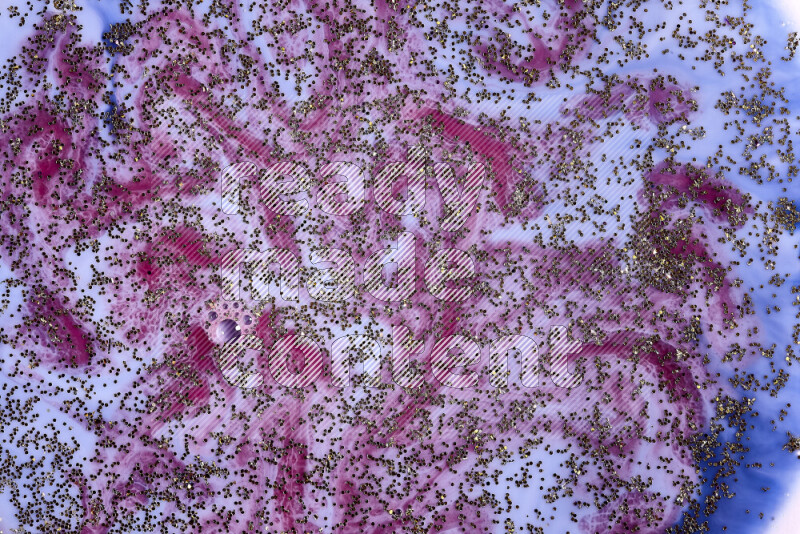 لقطة مقربة لبريق ذهبي متلألئ منتشر على خلفية من اللون الأزرق والأحمر في حركات دائرية