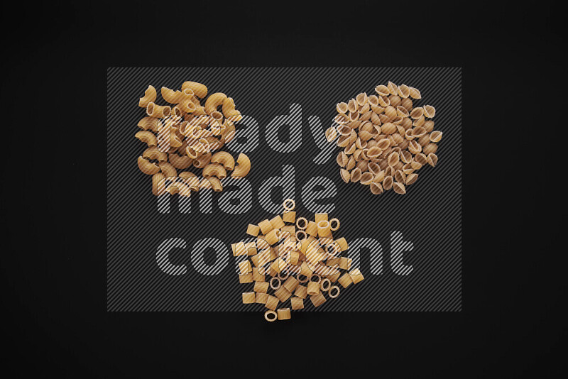 Different pasta types in bunches on black background