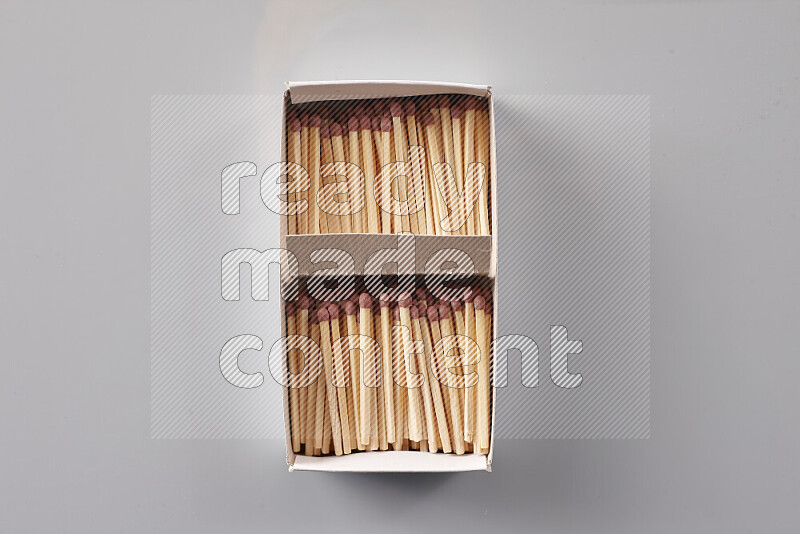 An open matchbox revealing wooden matches on a grey background