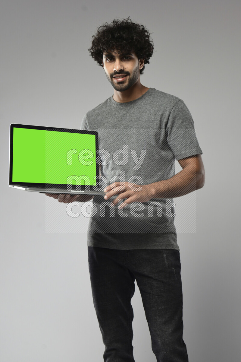 A man wearing casual standing and showing a laptop screen on white background