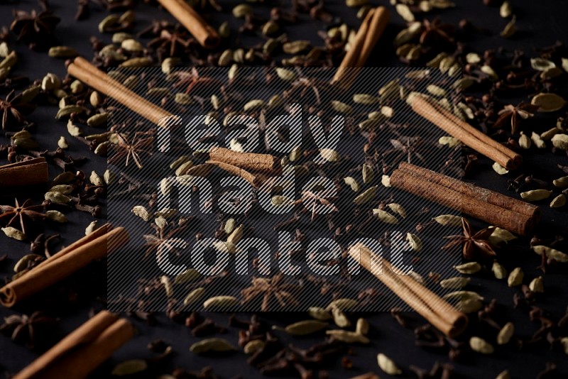 Cinnamon Sticks, Star anise, Cardamom and cloves on a black background