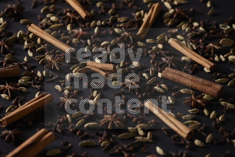 Cinnamon Sticks, Star anise, Cardamom and cloves on a black background