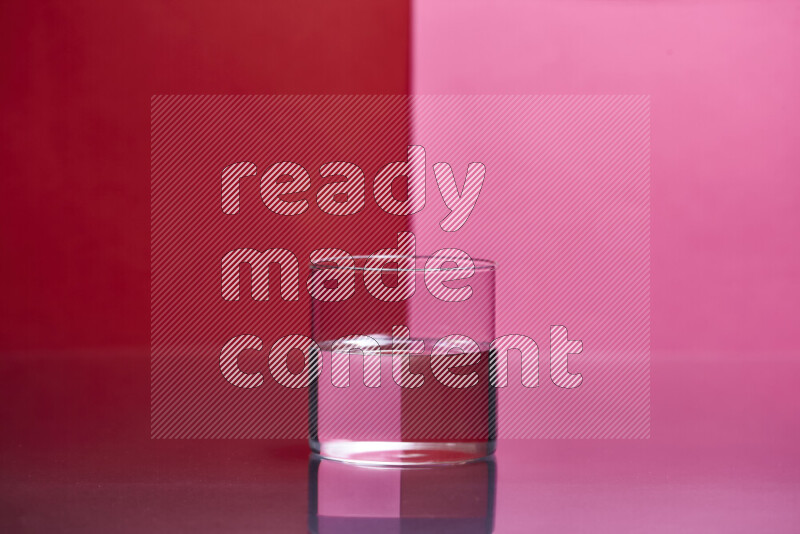 The image features a clear glassware filled with water, set against red and pink background