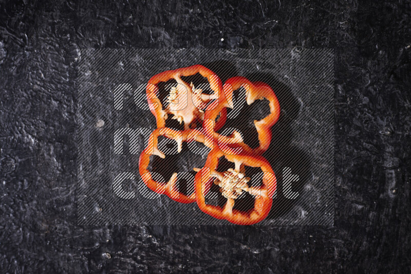 Red bell pepper slices on black background