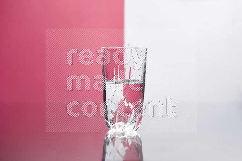 The image features a clear glassware filled with water, set against white and pink background