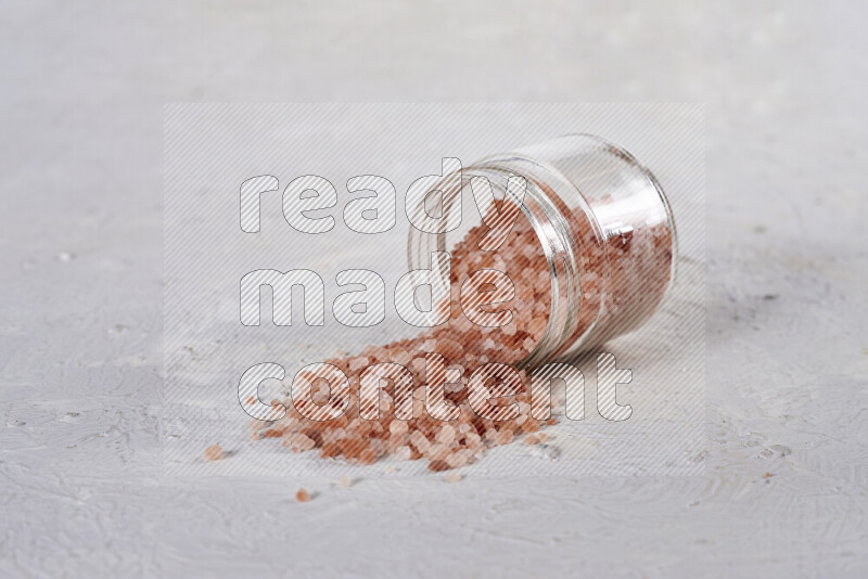 A glass jar full of coarse himalayan salt crystals on white background