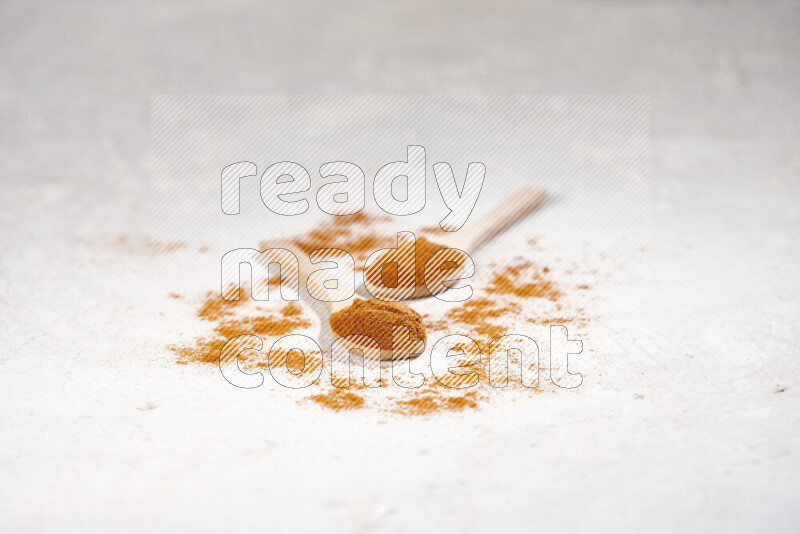 Two wooden spoons full of ground paprika powder on white background