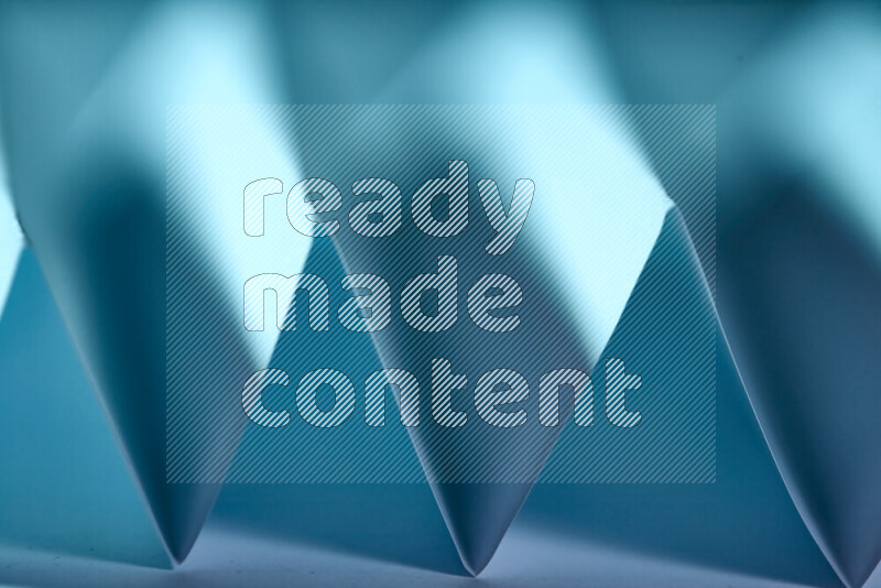 صورة مجردة مقربة تظهر طيات ورقية هندسية حادة بتدرجات اللون الأزرق