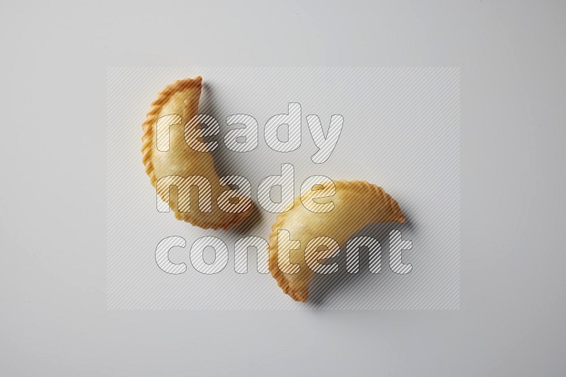 Two fried sambosa from a top angle on a white background