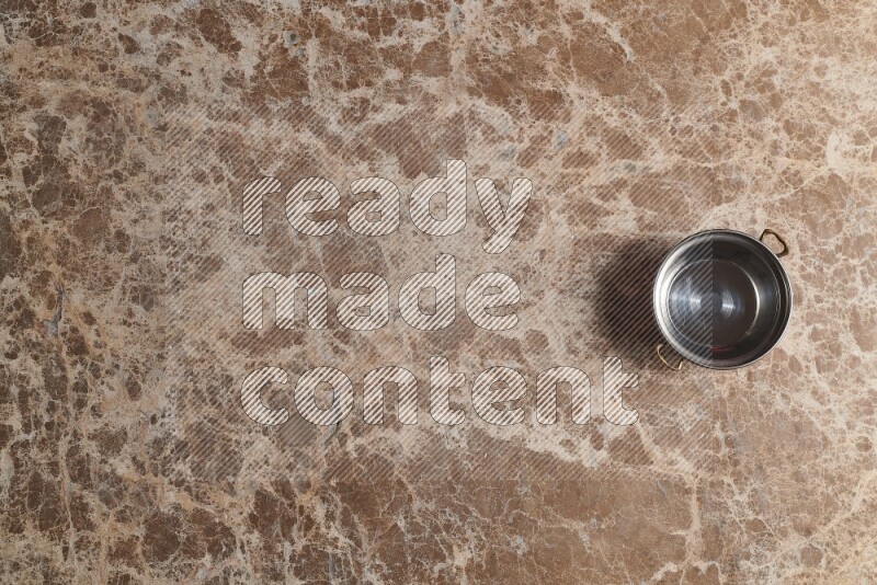 A small copper pot on beige marble background
