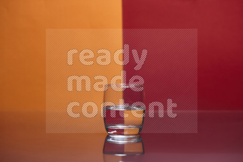 تظهر الصورة أواني زجاجية ممتلئة بالماء موضوعة على خلفية من اللونين البرتقالي والأحمر
