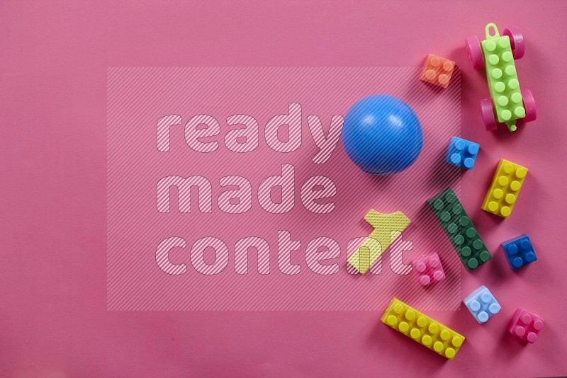 Plastic building blocks with balls on pink background in top view (kids toys)