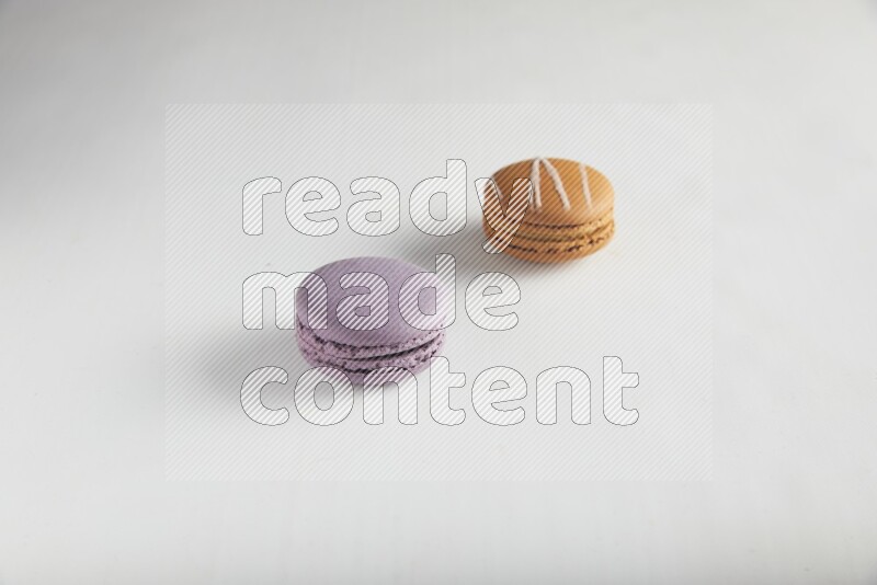 45º Shot of of two assorted Brown Irish Cream, and Purple Blueberry macarons on white background