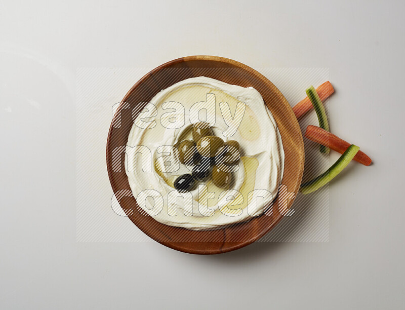 Lebnah garnished with whole olives in a wooden plate on a white background