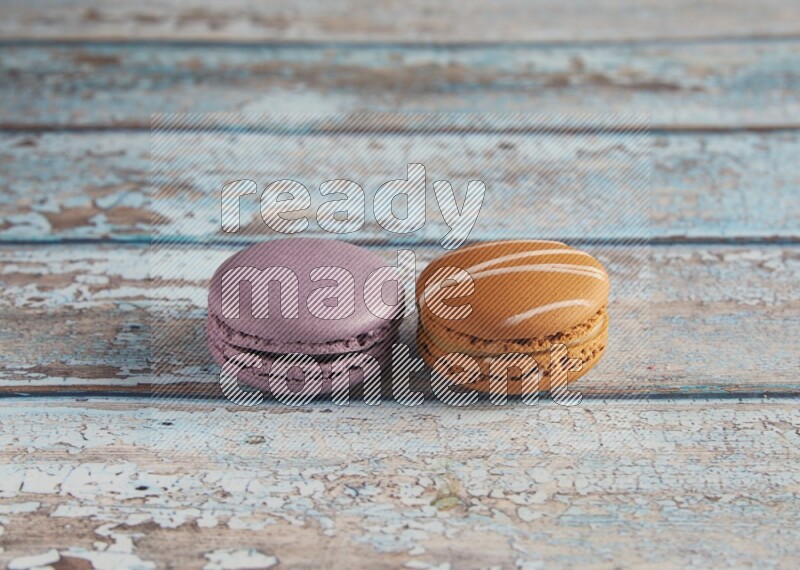 45º Shot of of two assorted Brown Irish Cream, and Purple Blueberry macarons  on light blue background