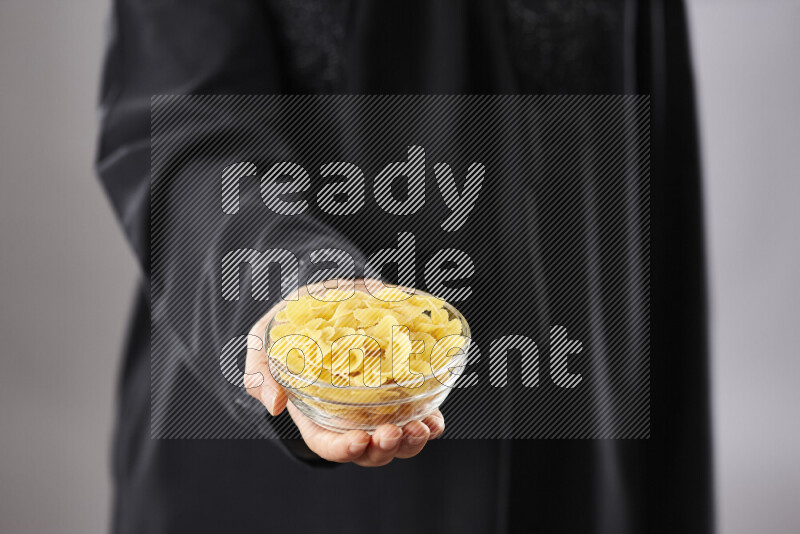 Woman in abaya holding different kinds of pasta in different positions