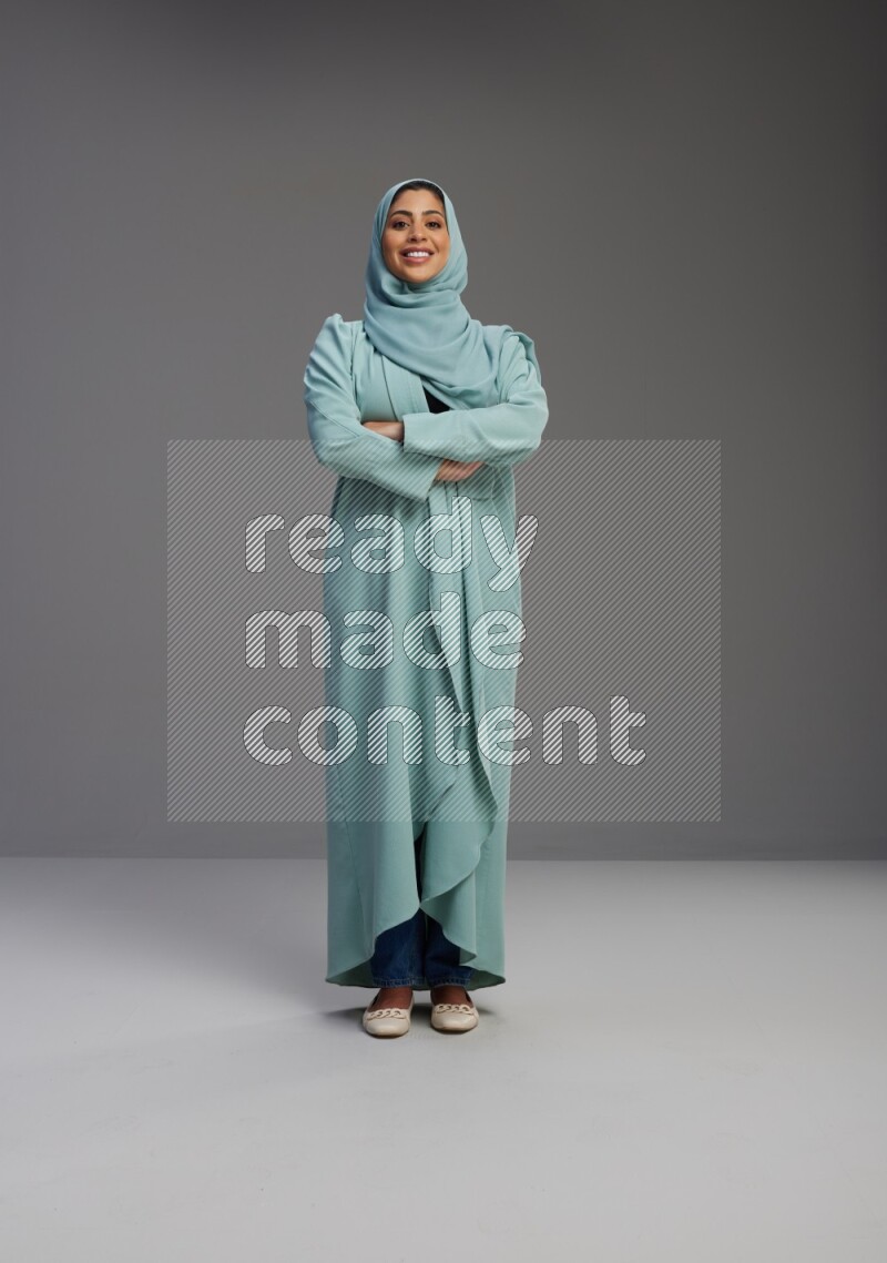 Saudi Woman wearing Abaya standing with crossed arms on Gray background