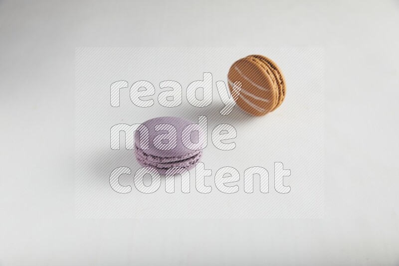 45º Shot of of two assorted Brown Irish Cream, and Purple Blueberry macarons on white background
