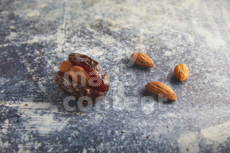 one almond stuffed madjoul dates on a rustic blue background