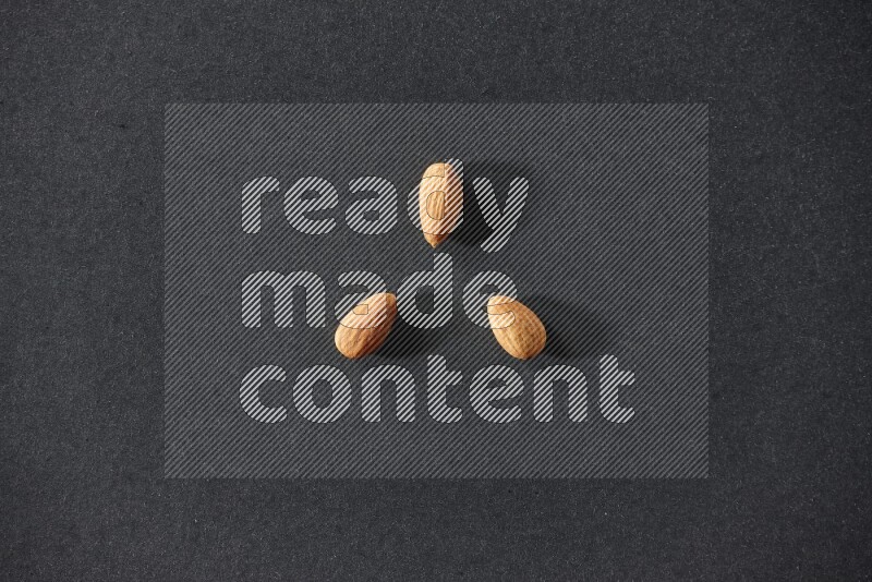 3 peeled almonds on a black background in different angles