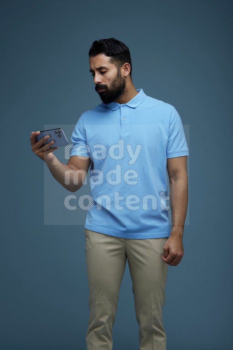 A man Watching a movie on his phone in a blue background wearing a Blue shirt