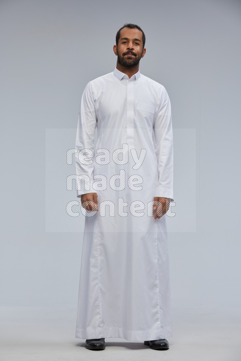 Saudi man Wearing Thob standing interacting with the camera on Gray background