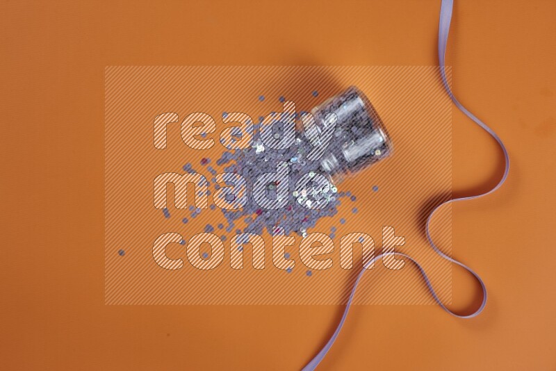 مجموعة من أدوات الخياطة والتفصيل أرجوانية اللون على خلفية برتقالية