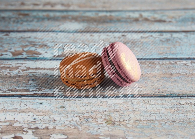 45º Shot of of two assorted Brown Irish Cream, and Purple Strawberry macarons  on light blue background