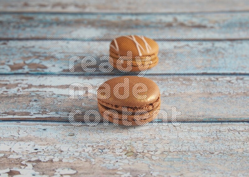 45º Shot of of two assorted Brown Irish Cream, and Brown Coffee macarons on light blue background