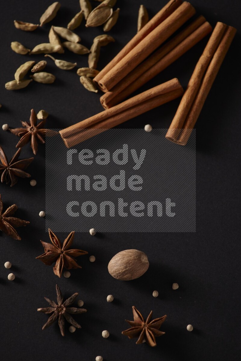 Cinnamon sticks, cardamom, star anise, nutmeg and white peppers on a black background