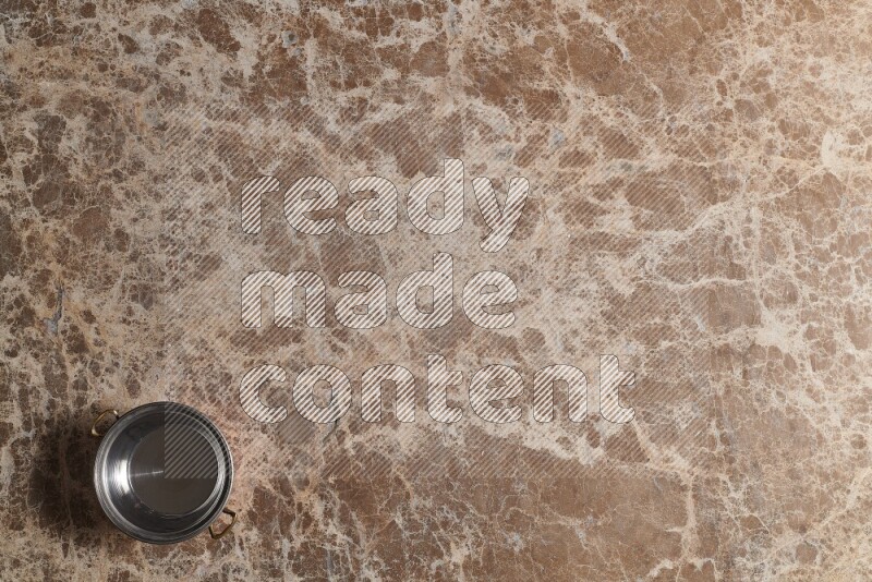 A small copper pot on beige marble background