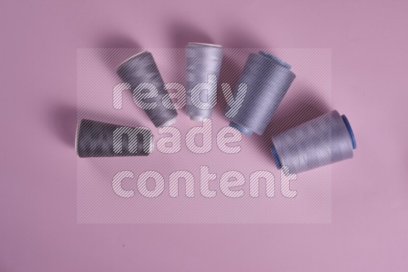 A grey collection of sewing and tailoring tools arranged on a pink background