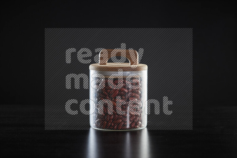 Red kidney beans in a glass jar on black background