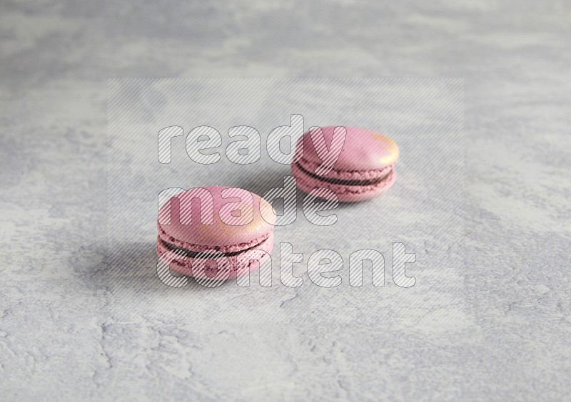 45º Shot of two Purple Strawberry macarons on white  marble background