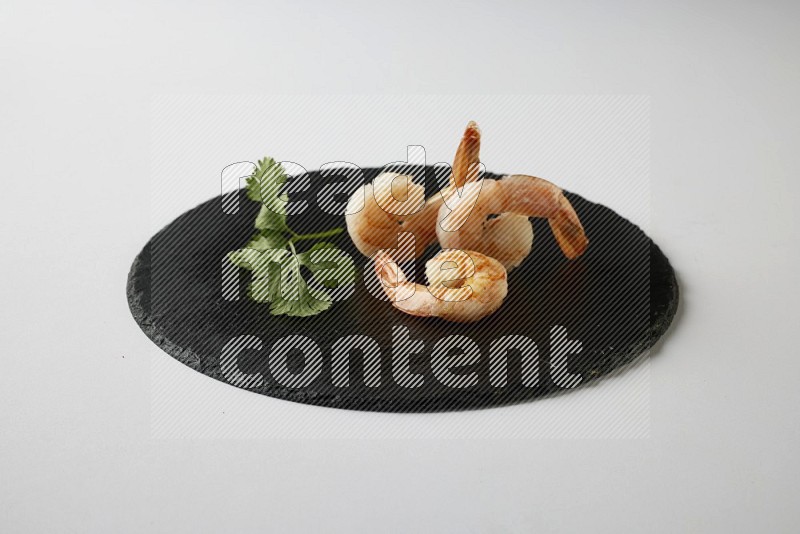 three grilled shrimp  on a black slate direct  on a white back ground