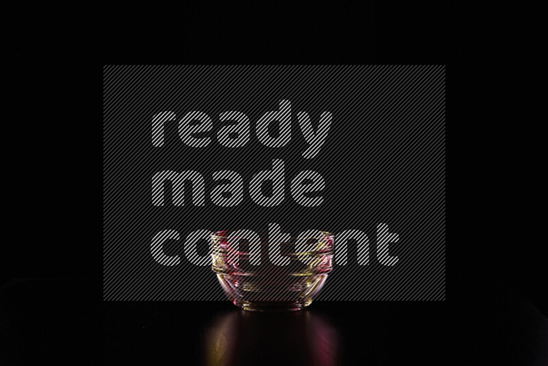 Glassware with rim light in red and yellow against black background