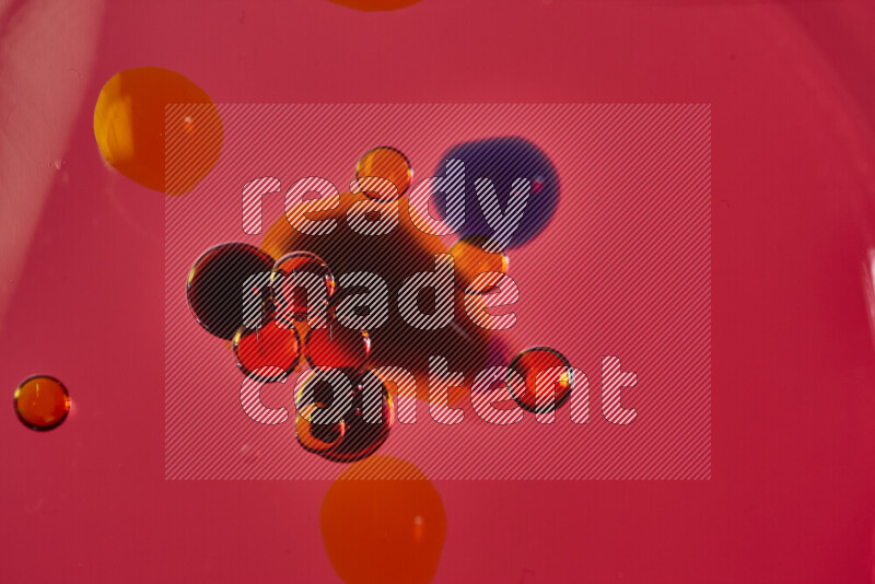 Close-ups of abstract red, blue and yellow watercolor drops on oil Surface on red background