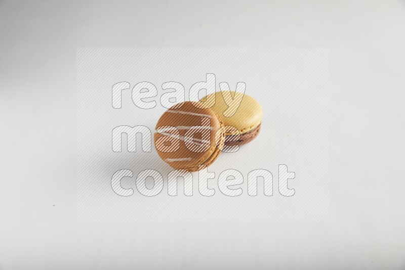 45º Shot of of two assorted Brown Irish Cream, and Yellow, and Brown Chai Latte macarons on white background