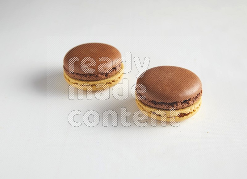 45º Shot of two Yellow and Brown Chai Latte macarons on white background