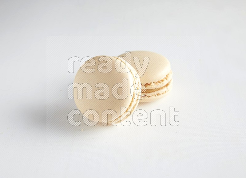 45º Shot of two White Caramel fleur de sel macarons on white background