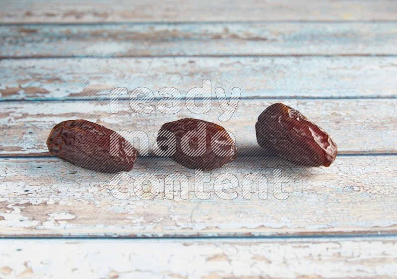 three madjoul dates on a light blue wooden background