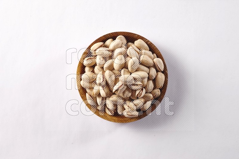Pistachios in a wooden bowl on white background